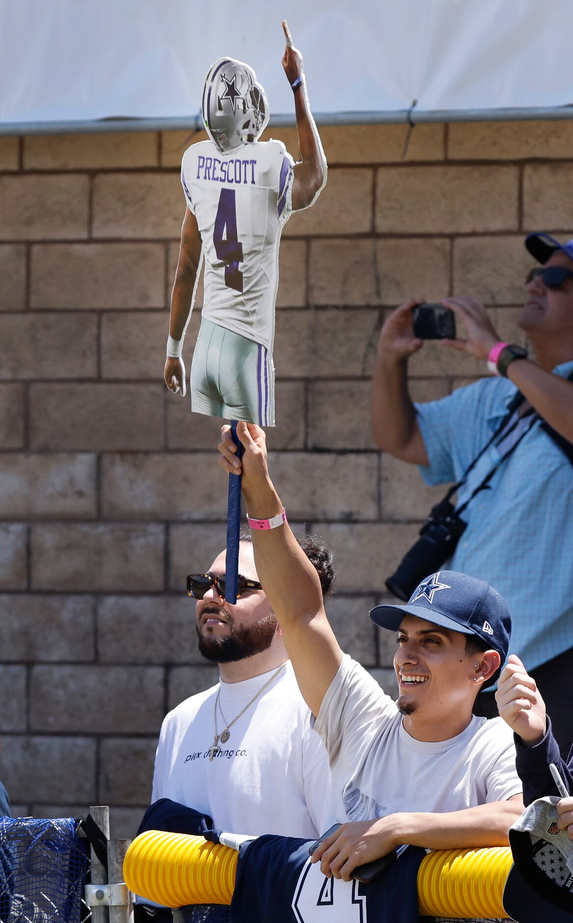 A Dallas Cowboys fan raises his stick cutout of quarterback Dak Prescott after getting his...