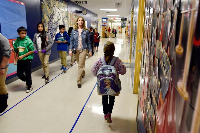 First-grader Halima Hassan walks through a hallway to her main classroom after working with...