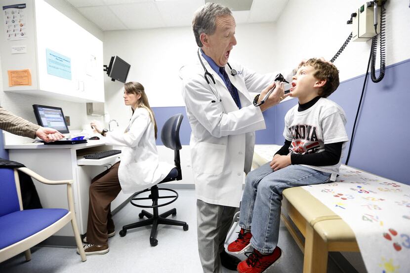 Dallas pediatric allergist Richard Wasserman asks Lawson Haney to open wide as he gives him...