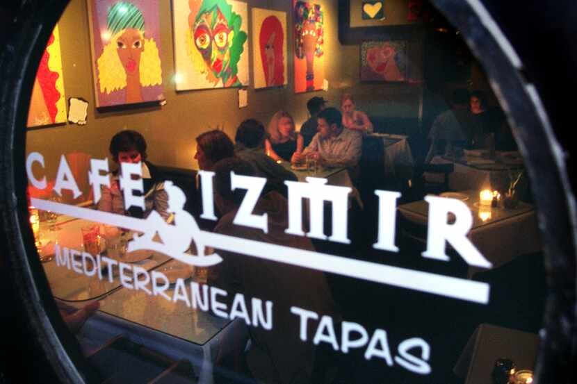 Cafe Izmir's inside dining room is packed on a Saturday night as seen through a round window. 