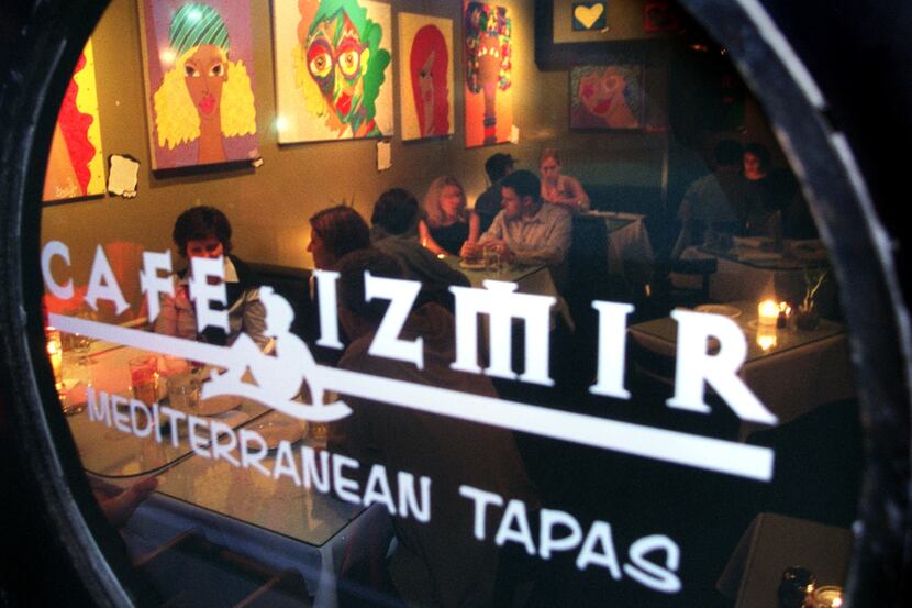 Cafe Izmir's inside dining room is packed on a Saturday night as seen through a round window. 