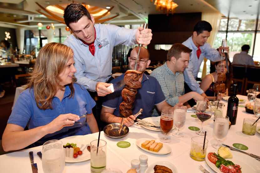 Gaucho Lucas Guski slices a piece of picanha for customer Kate Stein at the new Fogo de...