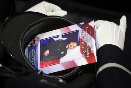 A memorial service program with a photo of Grand Prairie police officer Brandon P. Tsai sits...