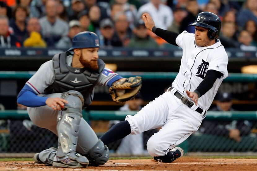 Detroit Tigers' Ian Kinsler, right, slides safely into home plate as Texas Rangers catcher...