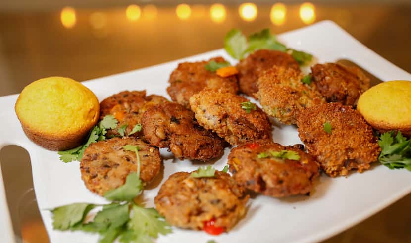 Black eyed pea fritters sit on a plate with cornbread muffins. The dish is made with black...