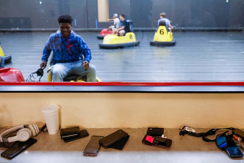 Cellphones remain outside of the glass window as L.D. Bell High School football players take...