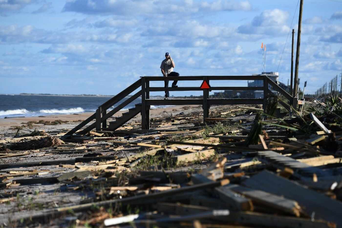 A man leans on a damaged boardwalk at a debris covered beach in St Augustine, Florida, on...