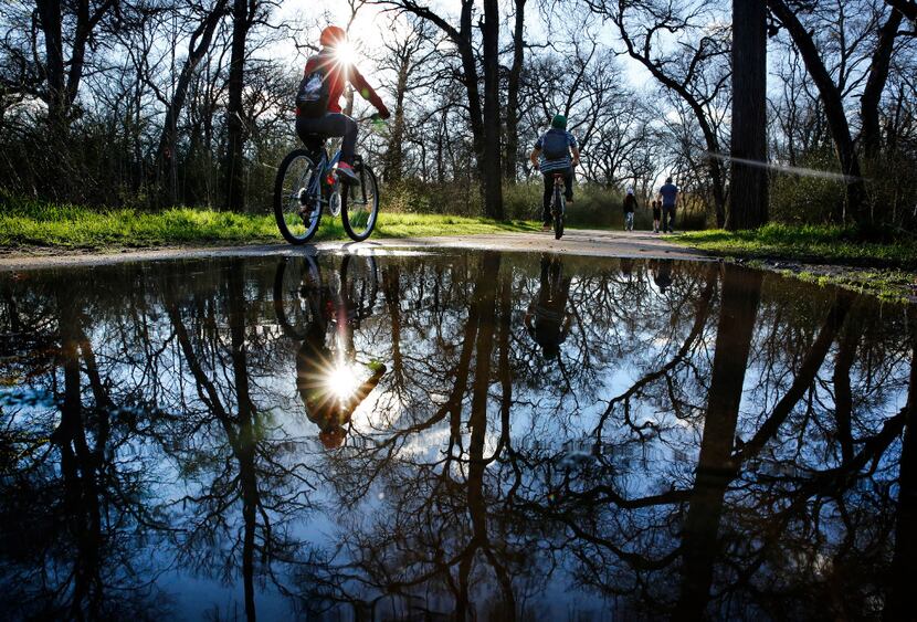 After overnight rains, cyclists and walkers navigate the water puddles along the paths of...