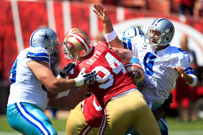 Dallas Cowboys quarterback Tony Romo (9) is hit as he throws by San Francisco 49ers Ahmad...