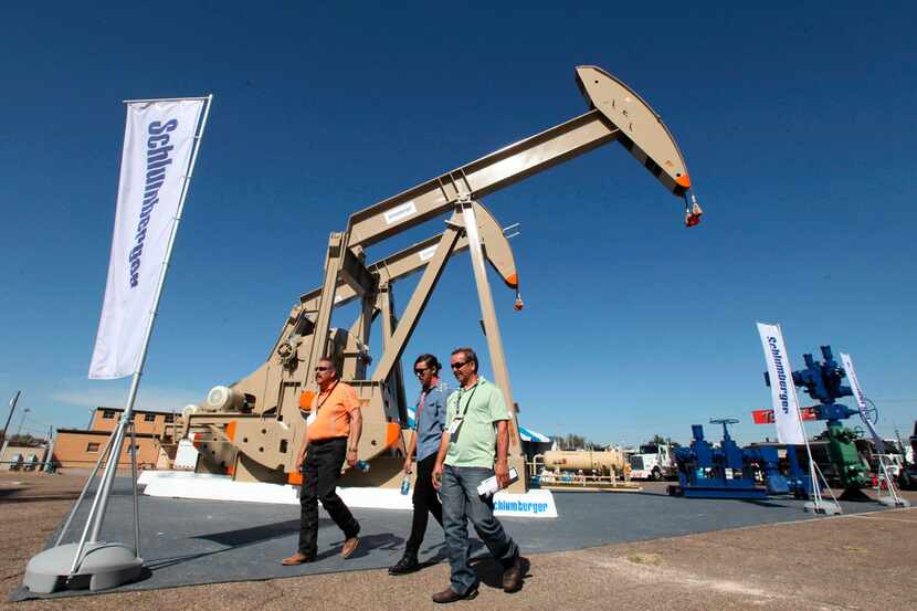 FILE - In this Oct. 18, 2016, file photo, oil show attendees walk past the Schlumberger...