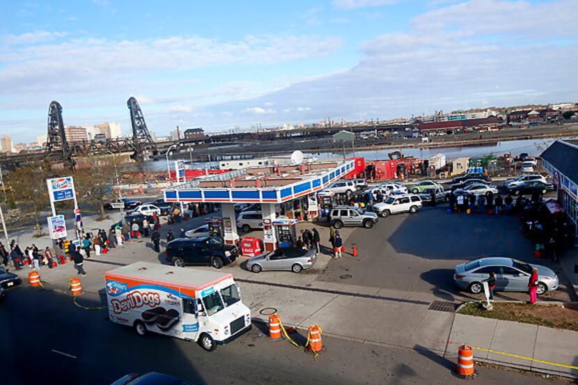 People and vehicles line up for gas Friday at a convenience store in Newark, N.J. Power...