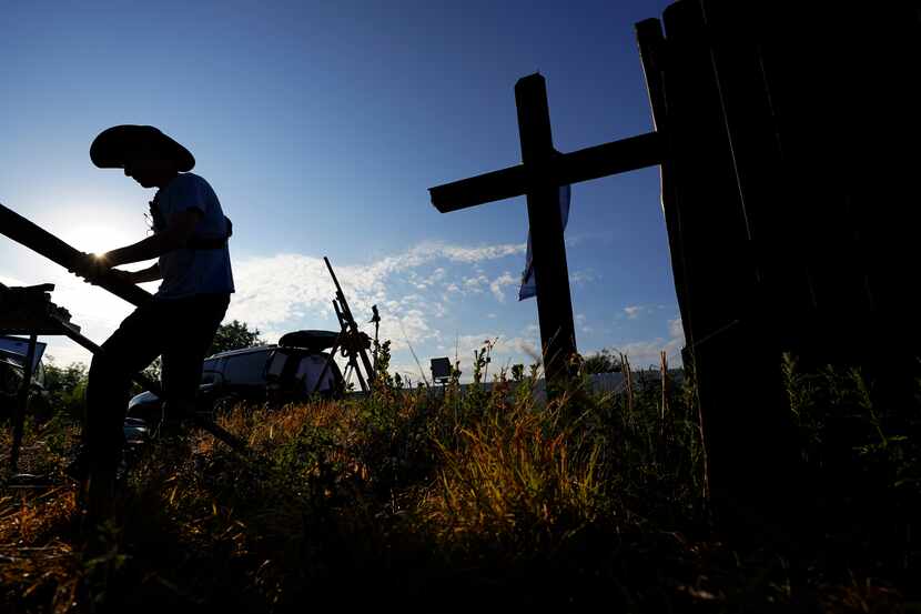 Roberto Marquez of Dallas builds and adds crosses to a make-shift memorial at the site where...