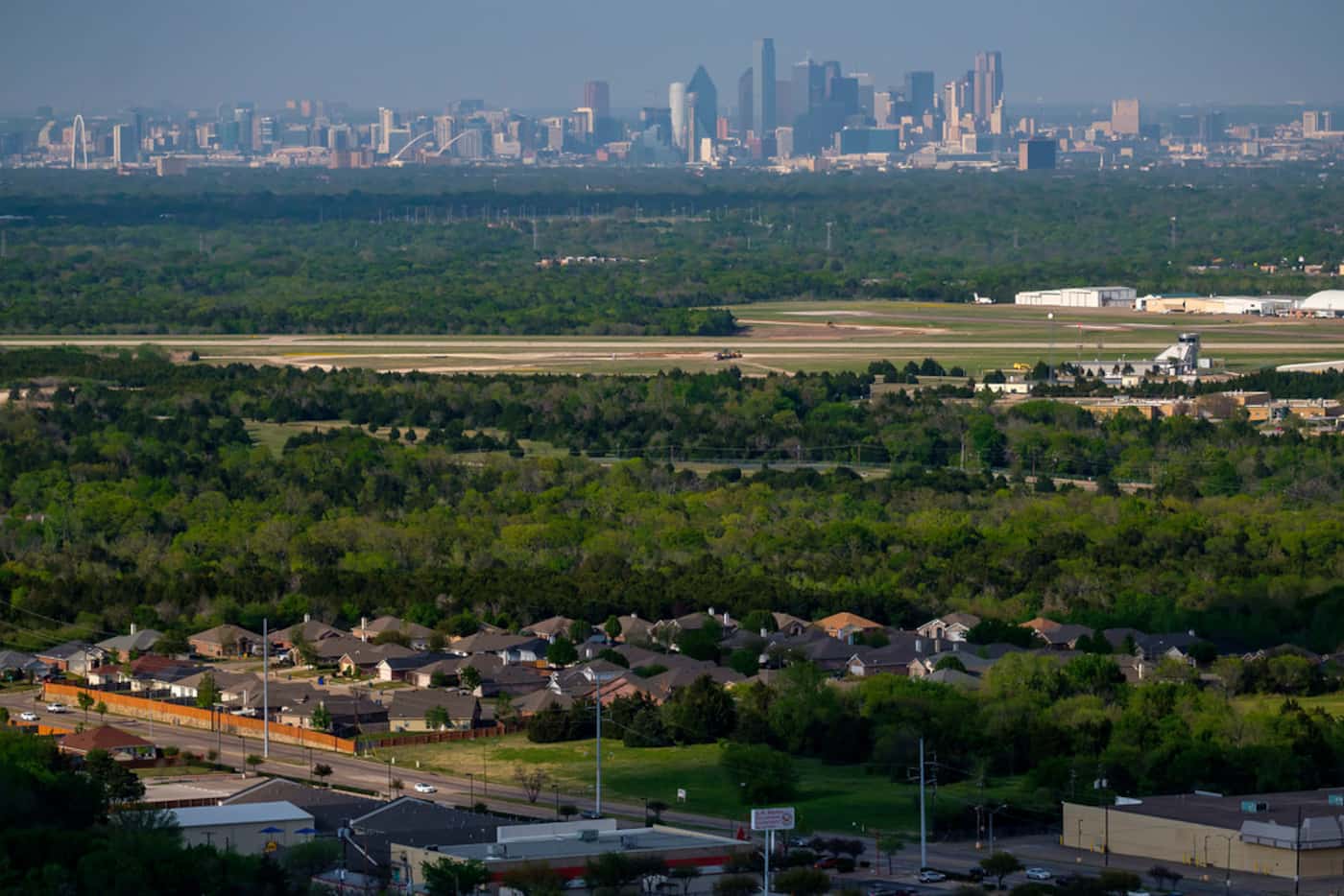 The downtown skyline is seen over Dallas Executive Airport and homes in the Red  Bird area...