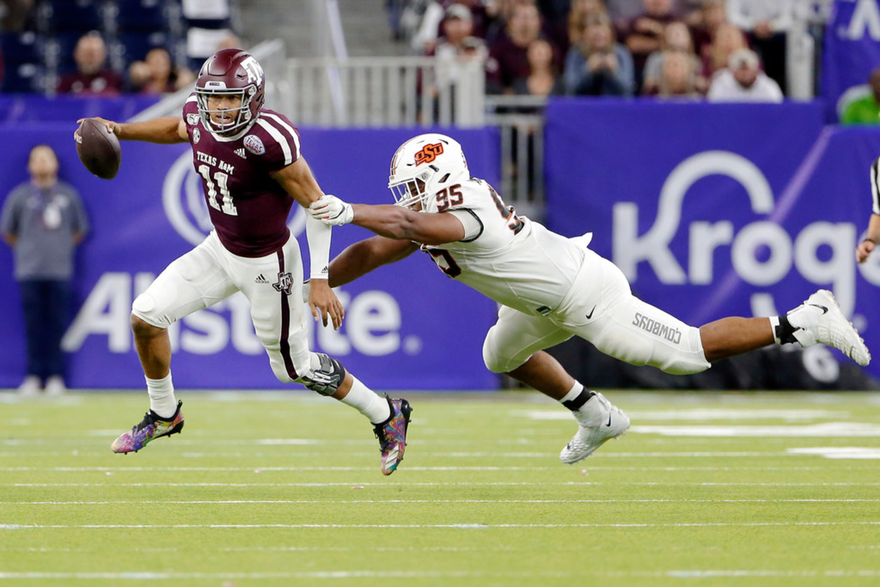 Texas A&M quarterback Kellen Mond (11) slips the tackle attempt by Oklahoma State defensive...