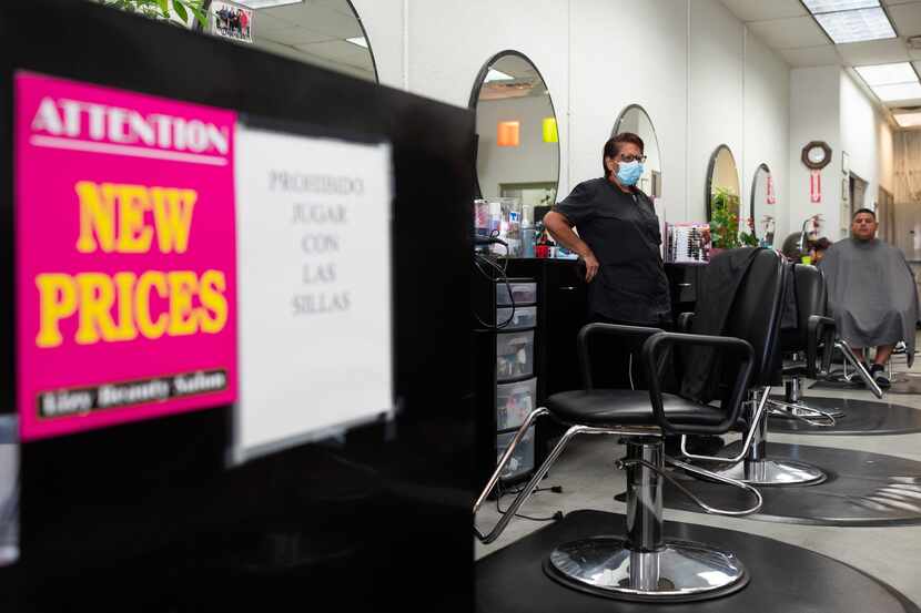 Signage for new prices is on display, left, as hair stylist Irene López waits by her work...