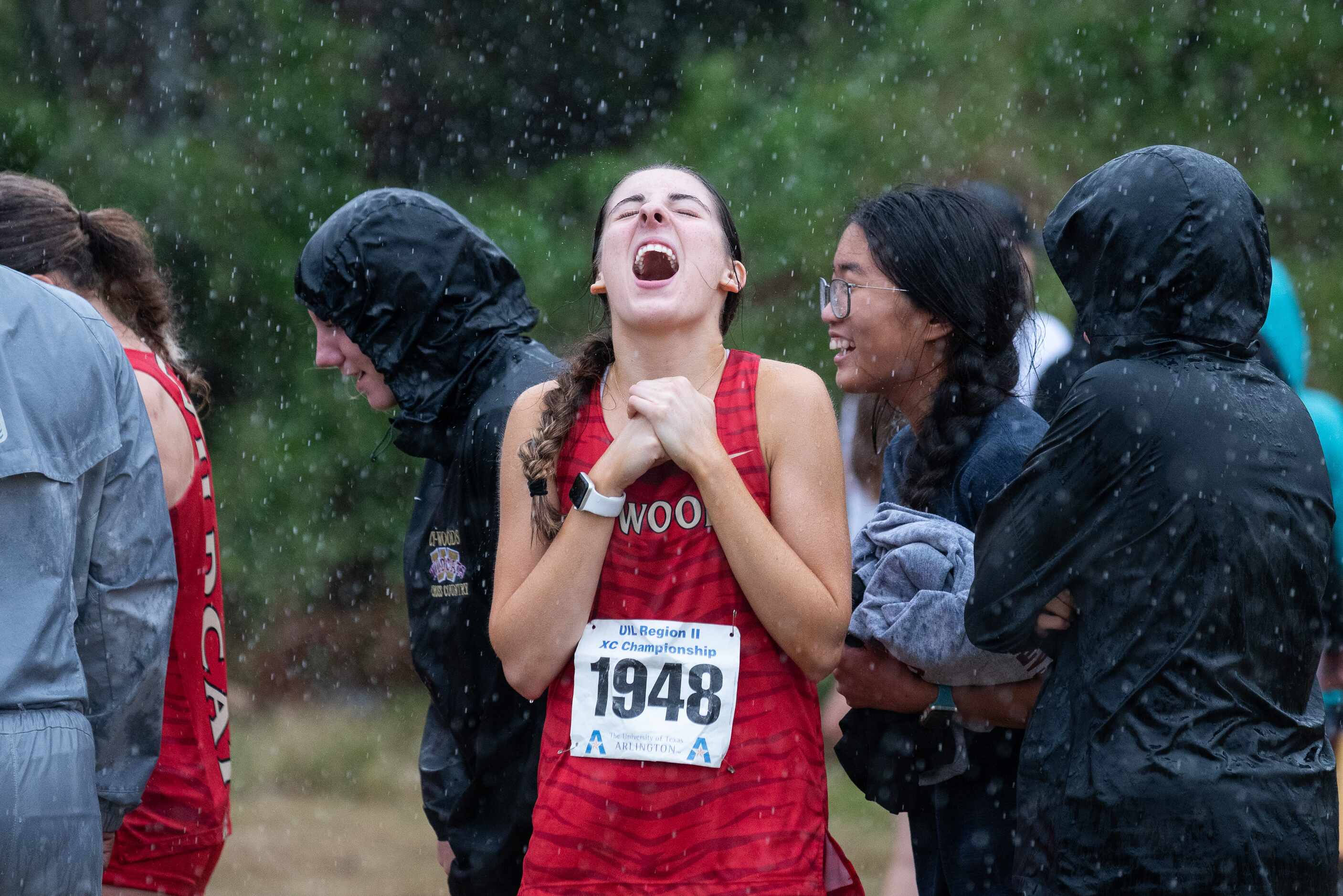 Cypress Woods runner Sydney Shores tastes the rain fall while standing with her team mates...