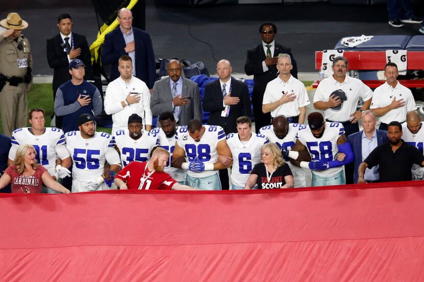 Dallas Cowboys link arm in arm during the National Anthem prior to the start of a game...