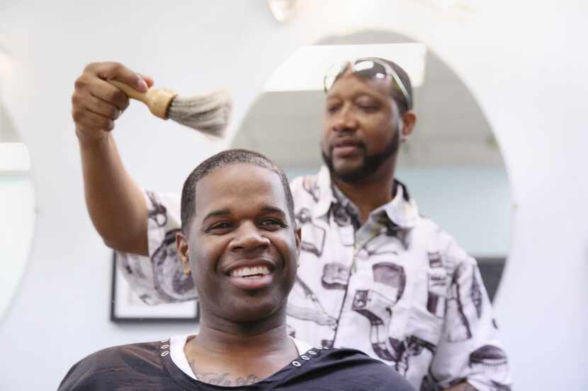 Barber Donric Mark, an independent contractor, cuts the hair of his brother, Dimario Mark,...