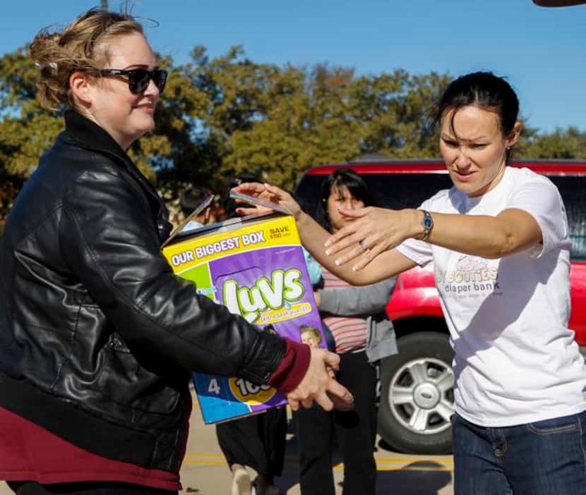 
Kiley Giles of McKinney (left) receives a box of diapers from Emily Padalino in the parking...
