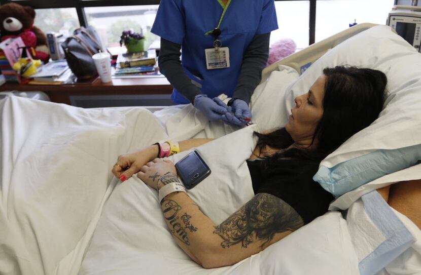 A nurse gives an injection to Roxanna Mayo as she lays in a hospital bed on April 8, 2015....