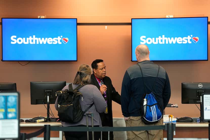 A Southwest Airlines employee works to assist travelers at a ticketing counter at...
