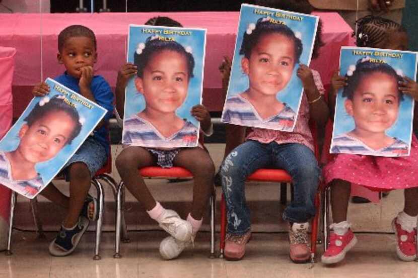 Children hold posters of Rilya Wilson, a 4-year-old in foster care in Florida who was...