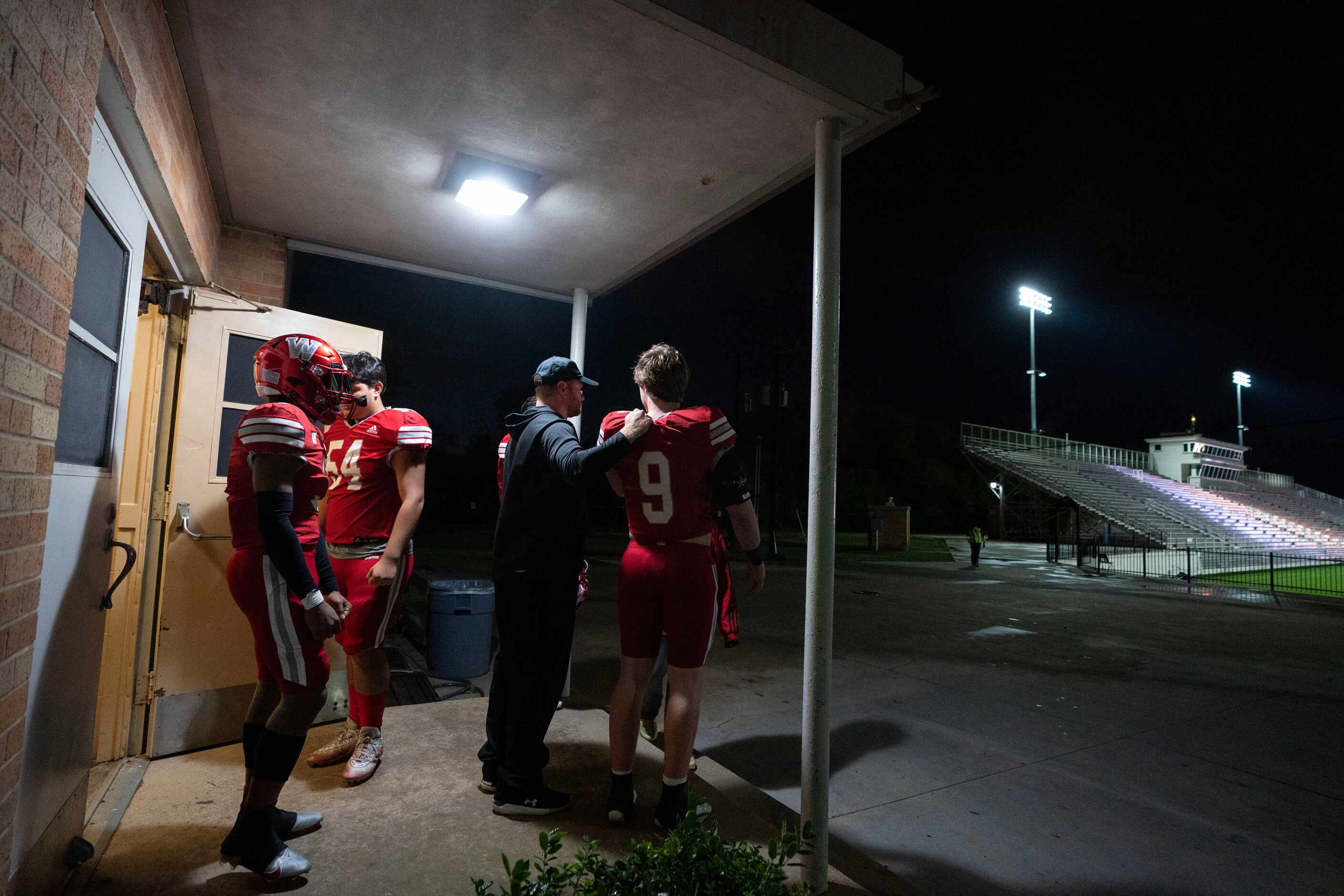 Woodrow Wilson players and coaches wait out a lightning delay before a high school football...