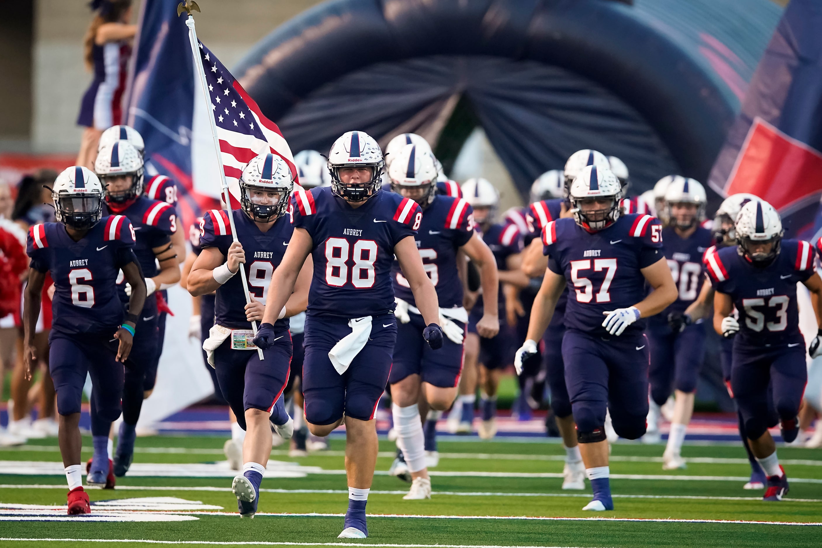 Aubrey quarterback Jaxon Holder (9) and tight end Wyatt Dyer (88) lead their team onto the...