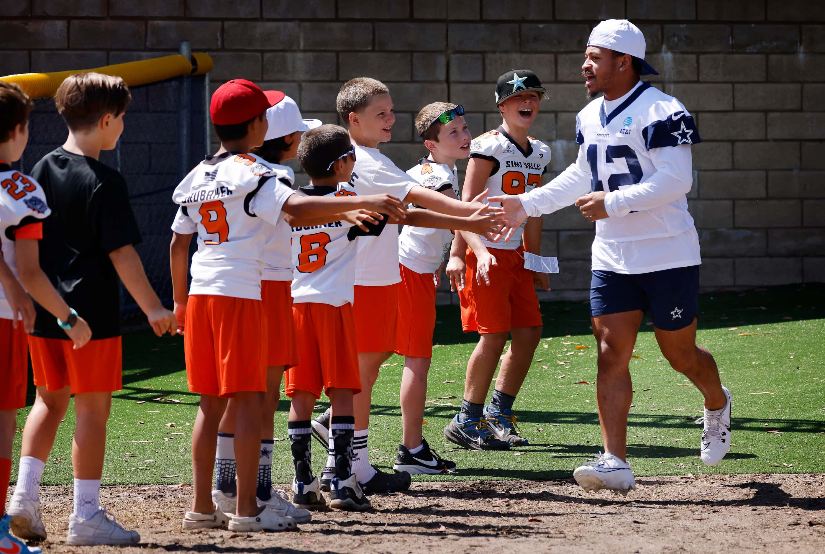 Dallas Cowboys running back Deuce Vaughn (42) slaps hands with Simi Valley Bulldogs youth...