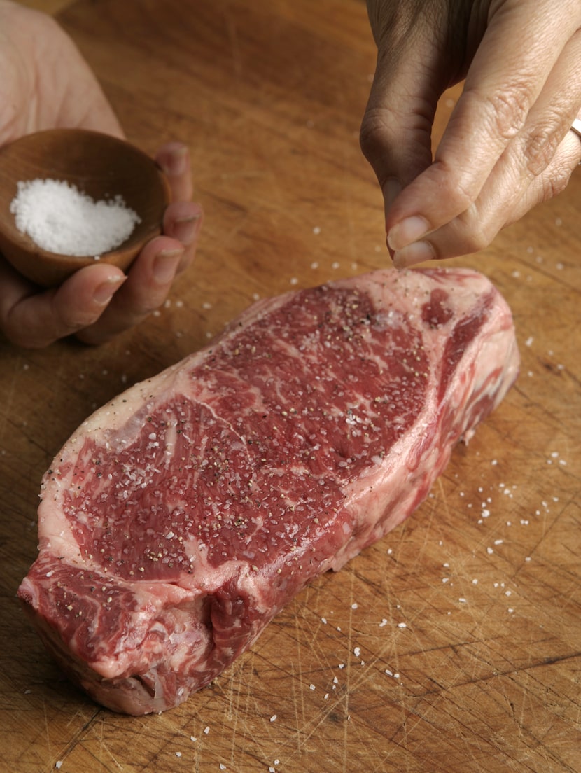 Seasoning a New York strip steak.