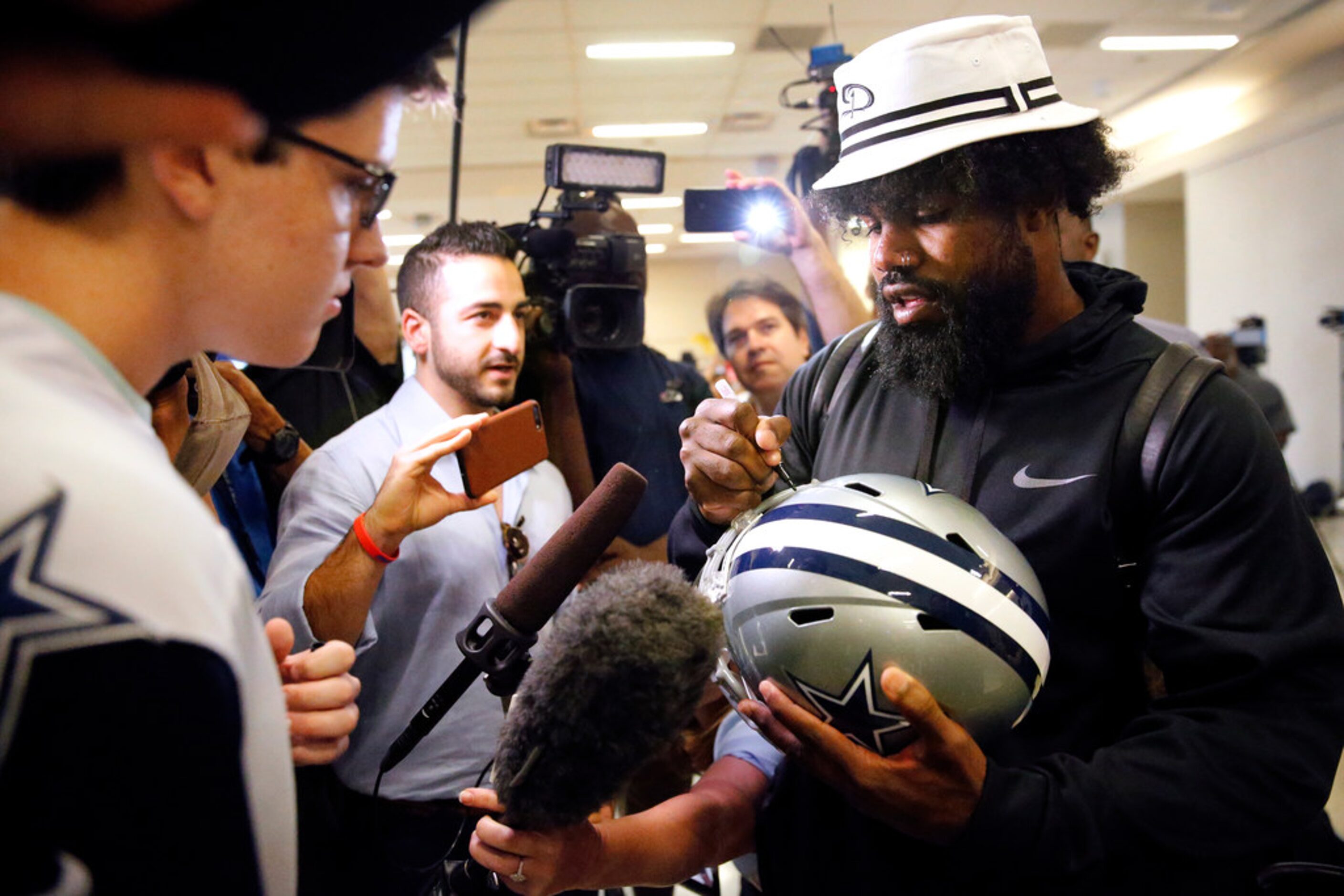 Dallas Cowboys running back Ezekiel Elliott signs a helmet for fan Drew Weinheimer of...