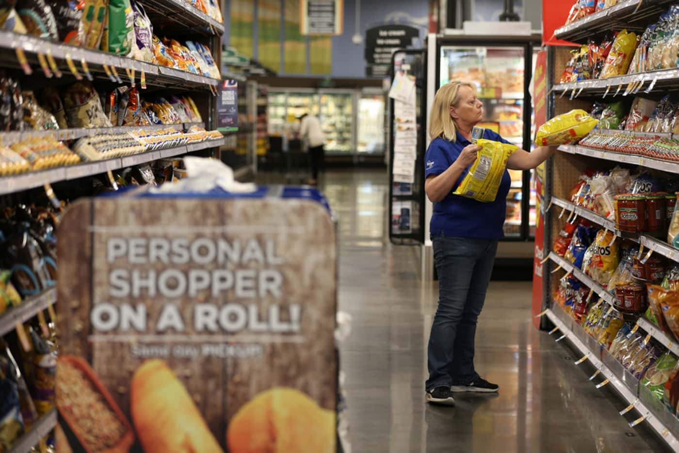 Diana Lynch, a ClickList associate, grabs chips off the shelf to fulfill an online order at...