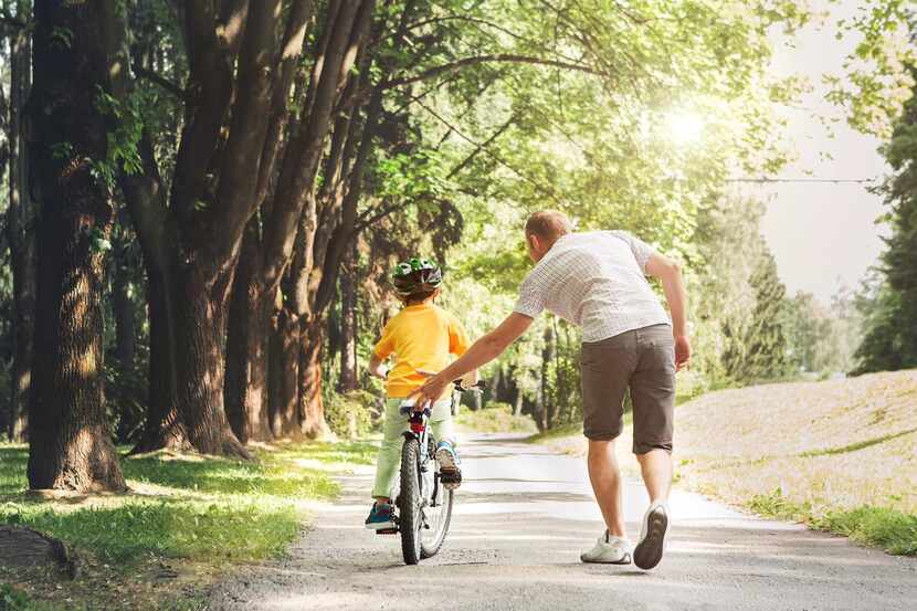 Un padre ayuda a su hijo aprender a usar una bicicleta.(GETTY PHOTOS)
