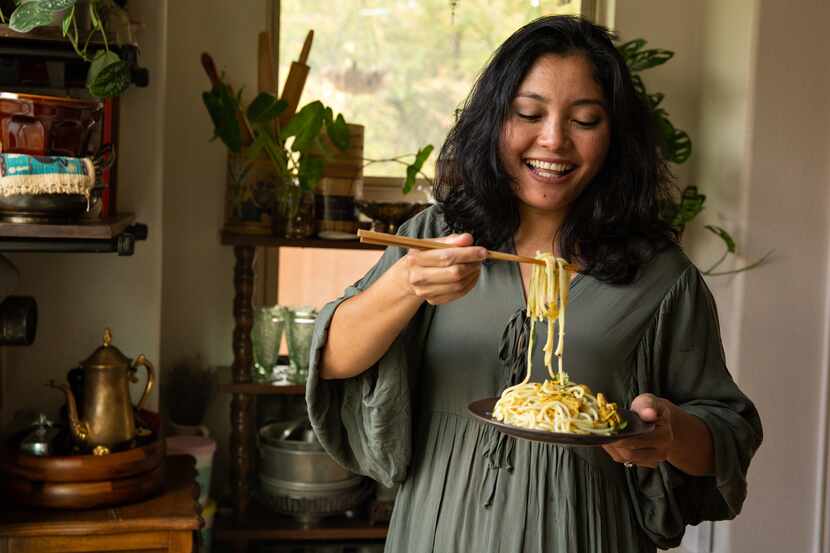 May Naing holds a plate of Nan Gyi Thoke, a popular dry noodle dish in Myanmar, in her home...
