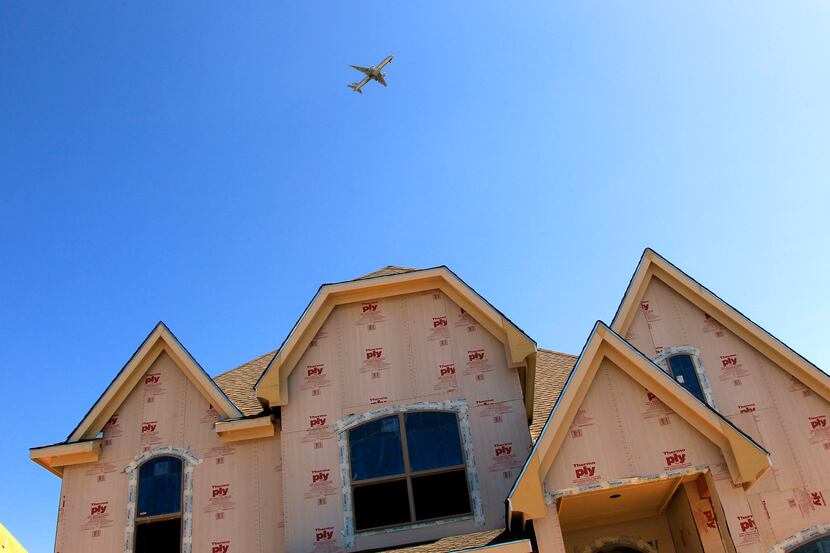 An airplane flies over homes under construction in the Carillon Development close to Dallas...