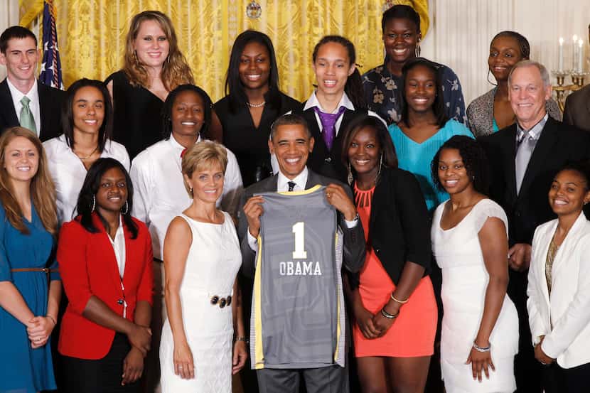 President Barack Obama holds up a team jersey as he stands with head coach Kim Mulkey, third...