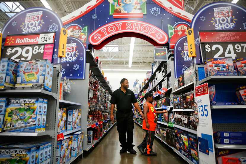 In this 2018 file photo, a father and his son walk down the toy aisle at a Walmart in Dallas.