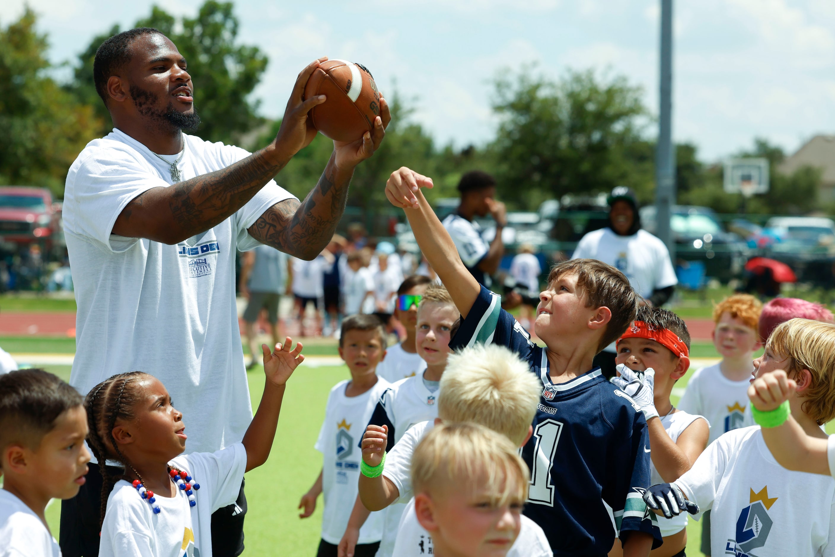 Dallas Cowboys linebacker Micah Parsons receives a pass as he interacts with young football...