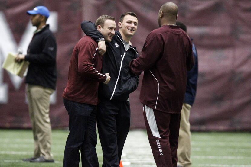 Texas A&M quarterback Johnny Manziel, middle, gives offensive coordinator Jake Spavital a...