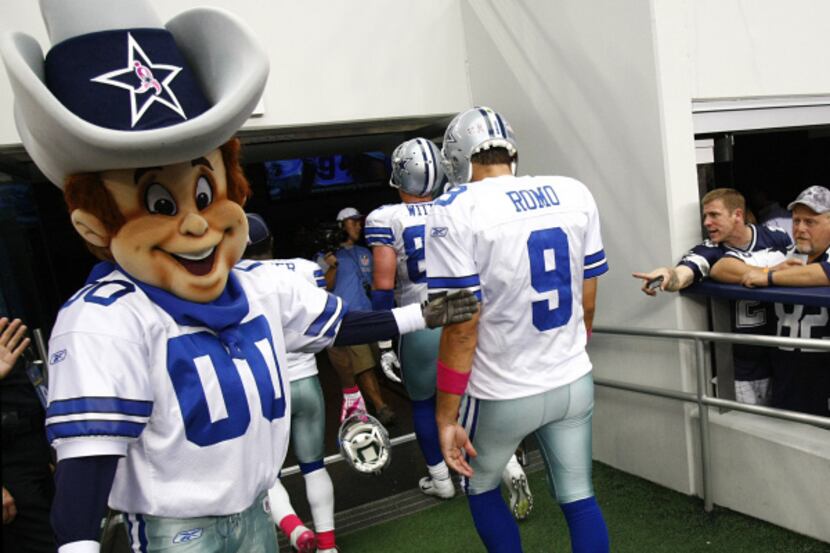 Dallas Cowboys mascot Rowdy gives a tap to quarterback Tony Romo (9) as he walks off the...