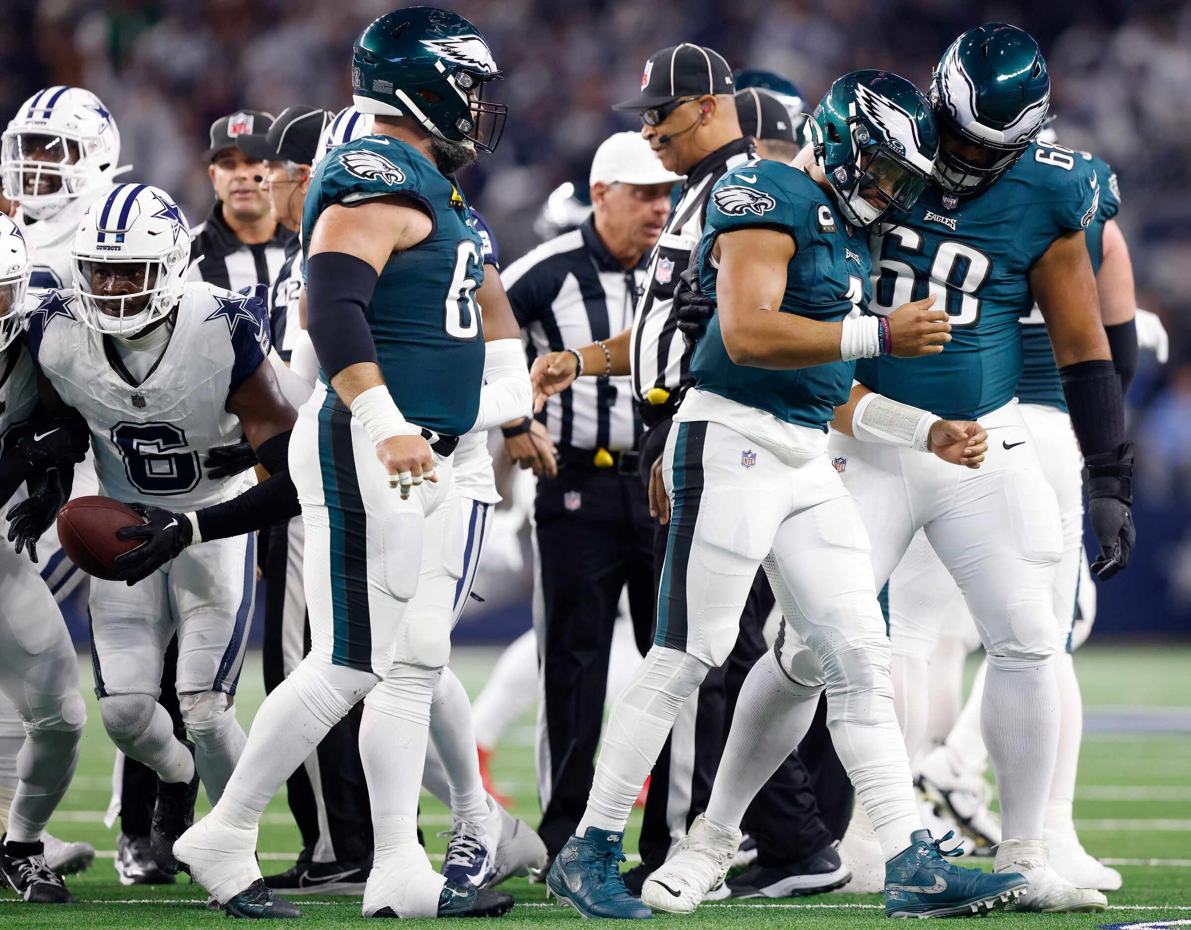 Philadelphia Eagles quarterback Jalen Hurts (1) is helped to the sideline by teammate Jordan...