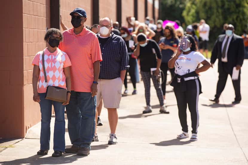 Voters wait in line during the first day of early voting at the South Garland Branch Library...