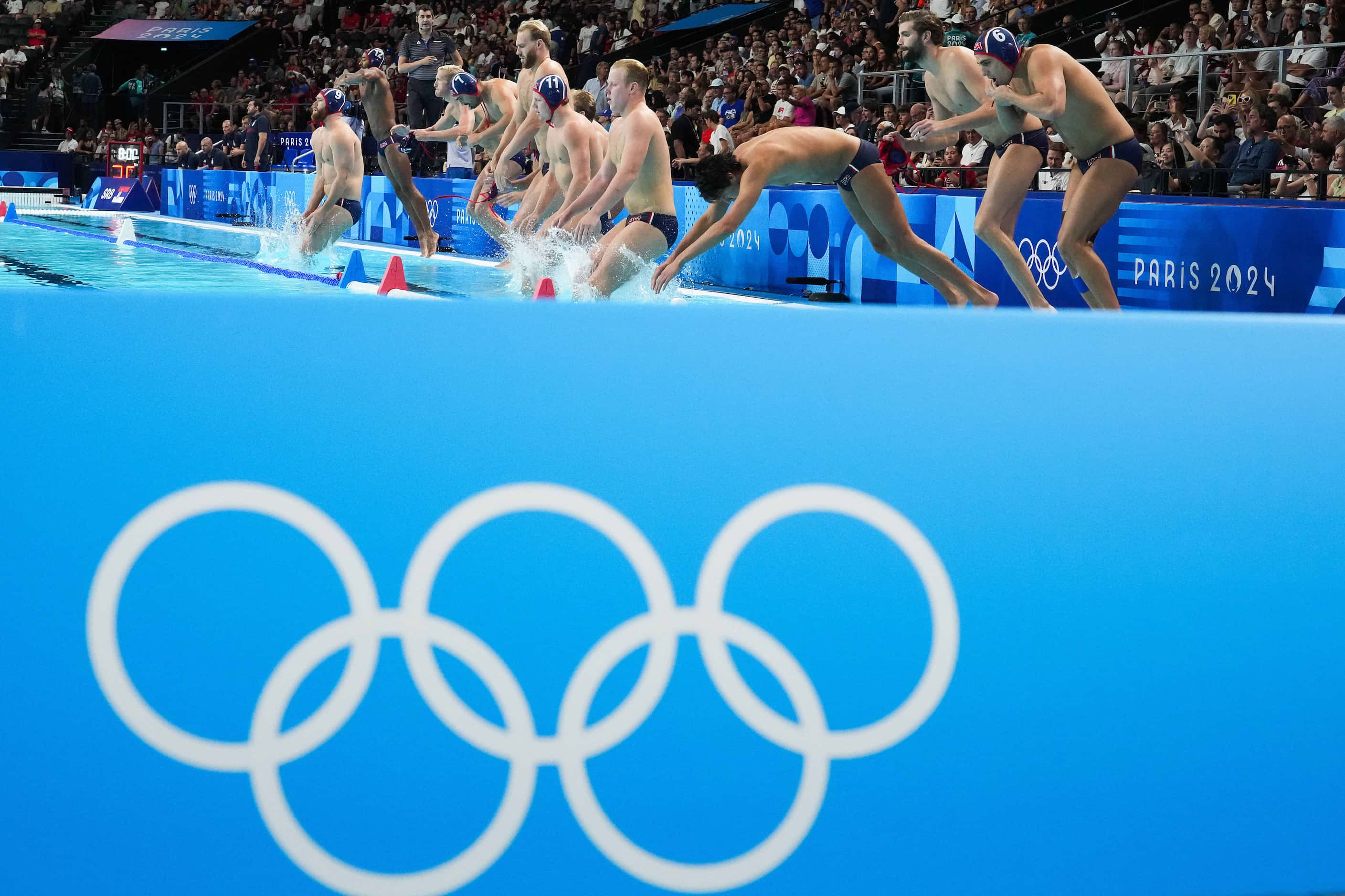 Team USA leaps in to the pool for a men’s water polo semifinal against Serbia at the 2024...