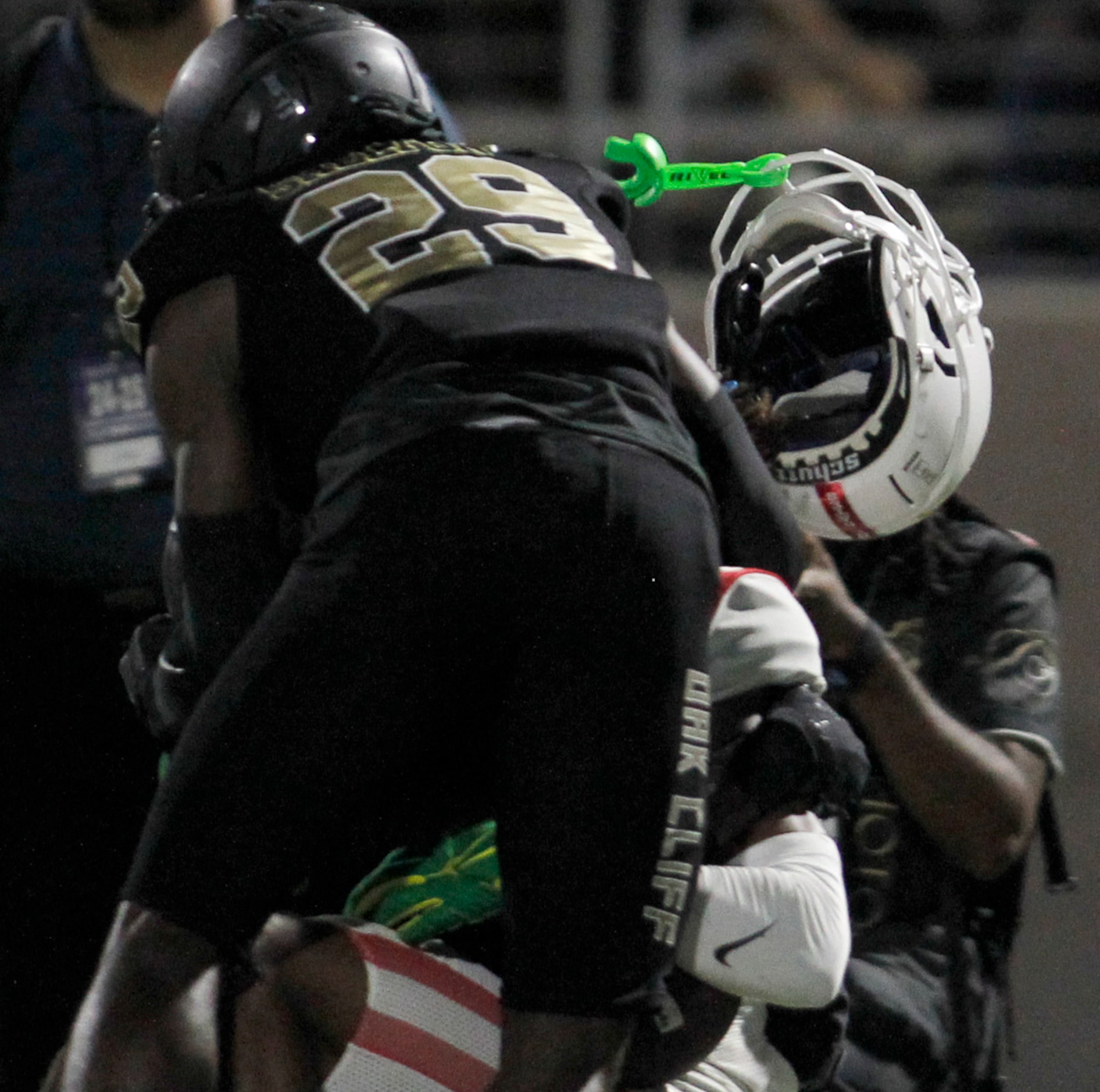 Duncanville receiver Dakorien Moore (1), background, has his helmet knocked off by the...