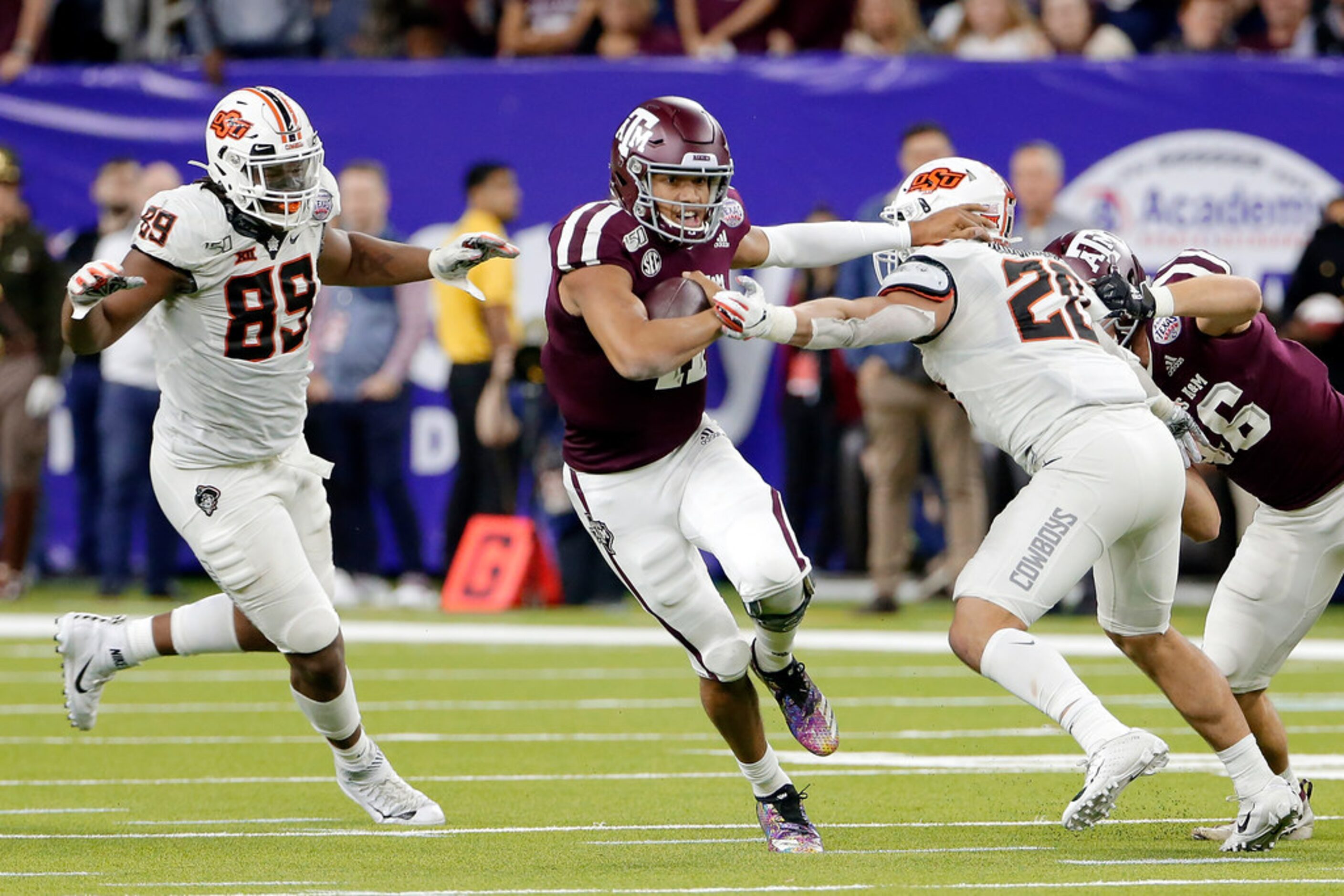 Texas A&M quarterback Kellen Mond (11) gets through the hole between Oklahoma State...