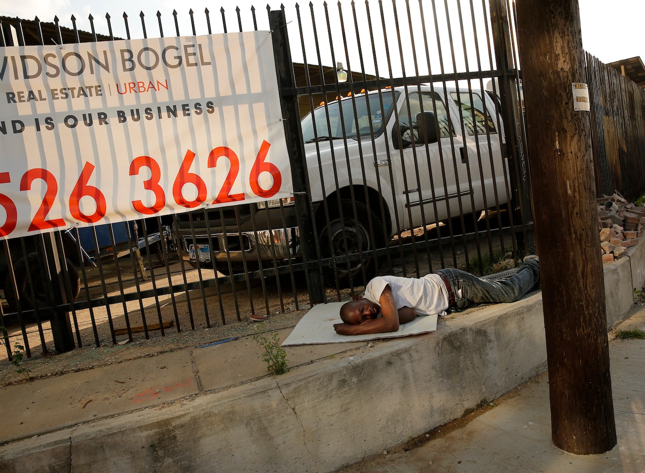 A man sleeps on a piece of cardboard along Singleton Blvd across the street from Trinity...