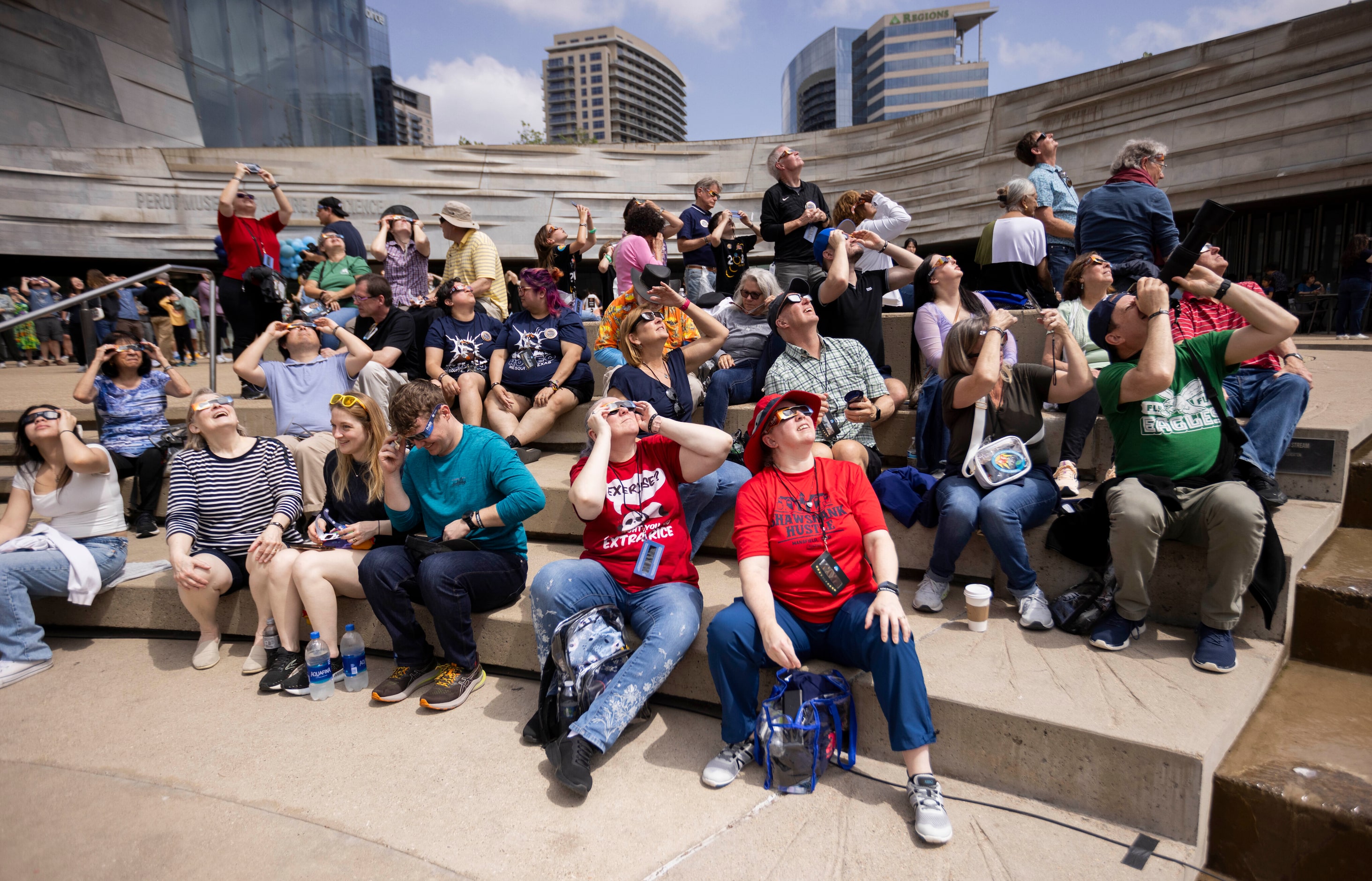 People watch the eclipse during the Great North American Eclipse event at the Perot Museum...