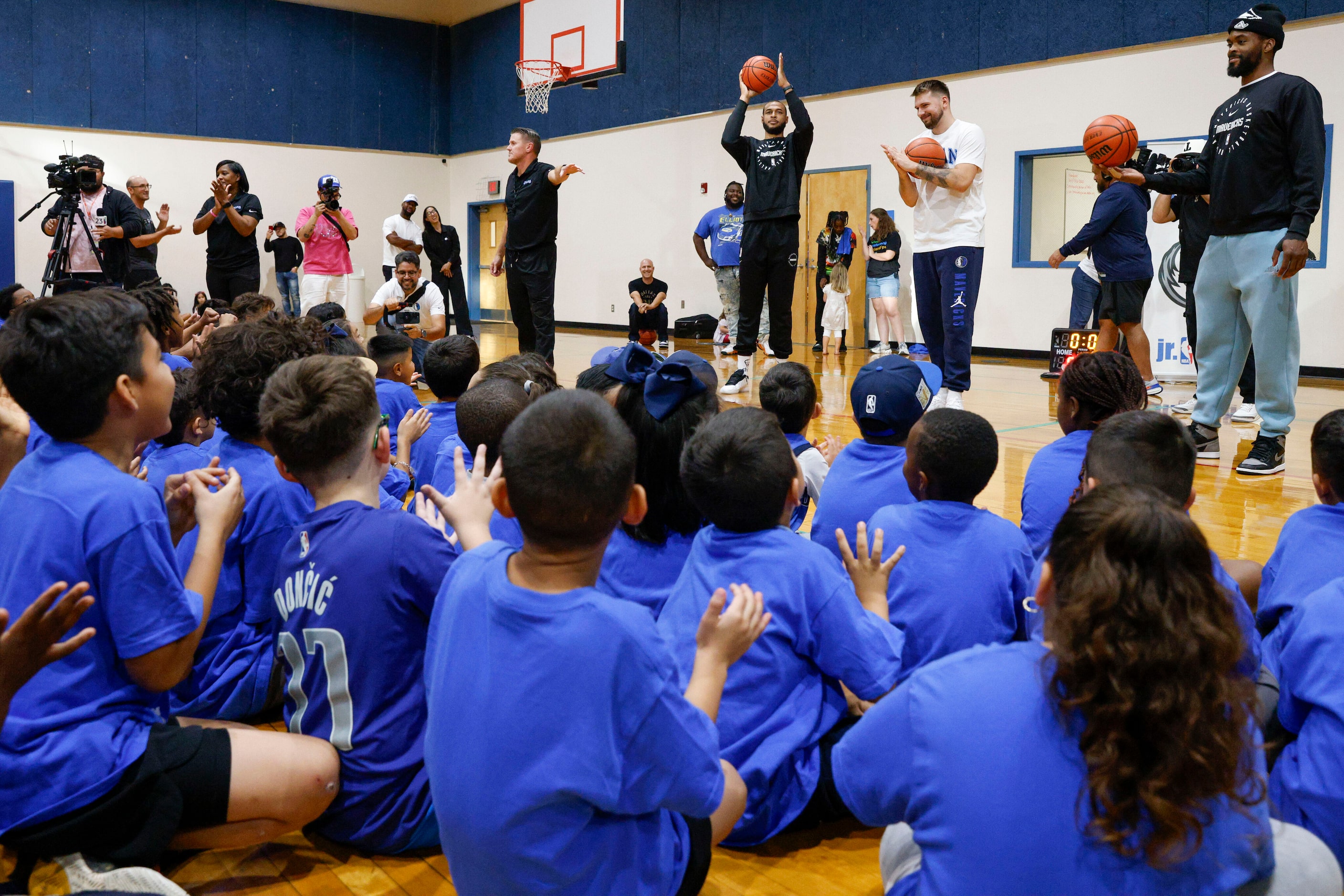 Children clap as they thank Dallas Mavericks players Daniel Gafford, Luka Doncic and Naji...