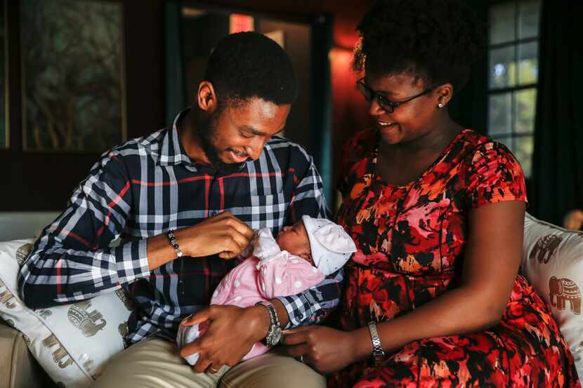 Derrick (left) and Mech Metiege hold Sekani, their daughter who was born during Sunday...
