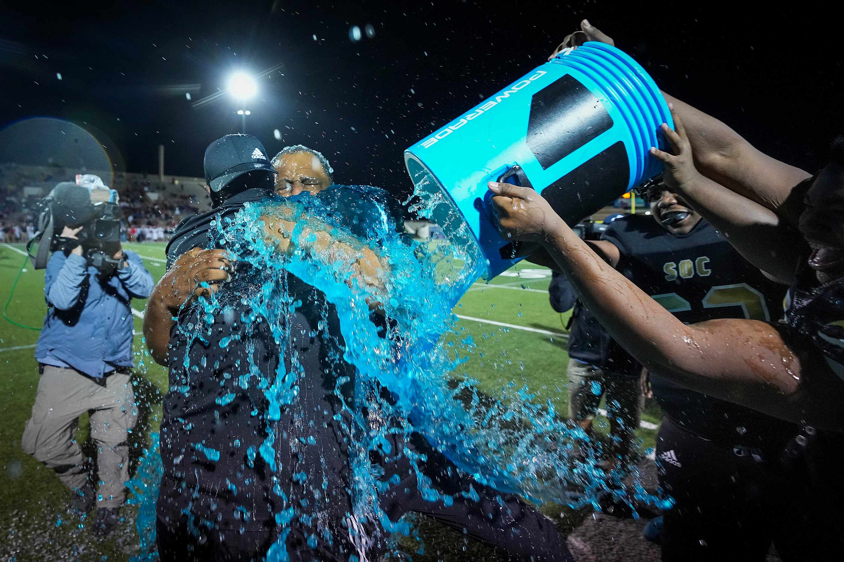 South Oak Cliff head coach Jason Todd is doused by his players as he hugs assistant coach...
